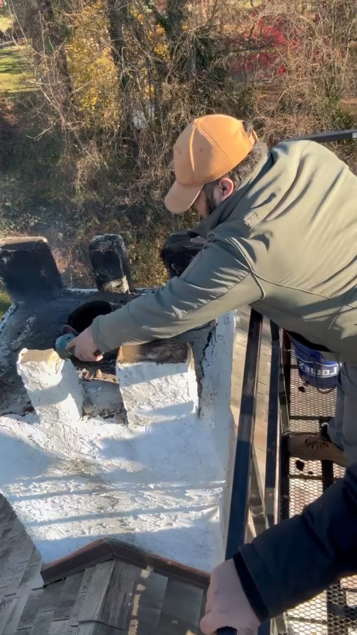 Technician reaching across a chimney crown from a work platform