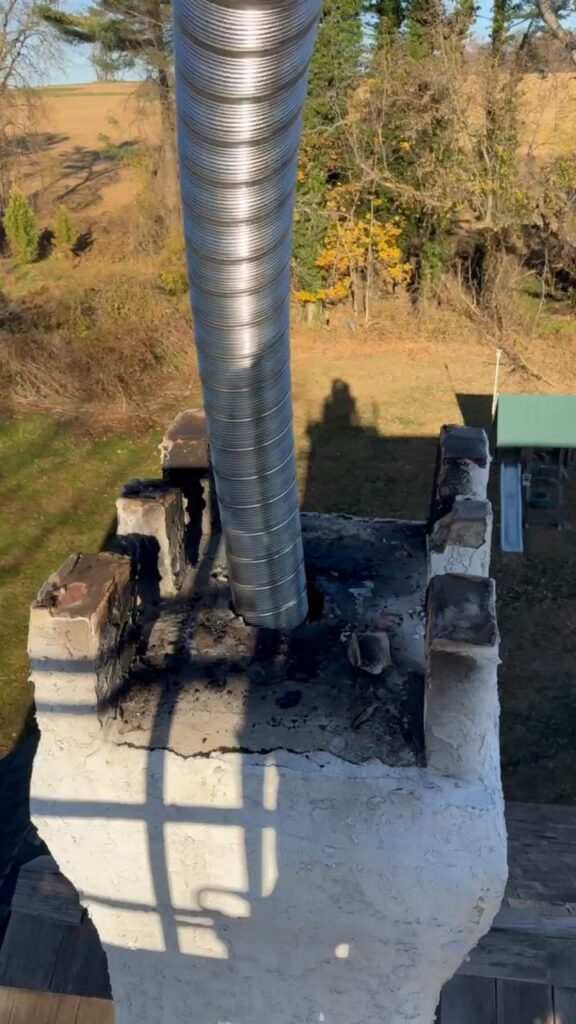 Metal chimney liner running out of a masonry chimney crown