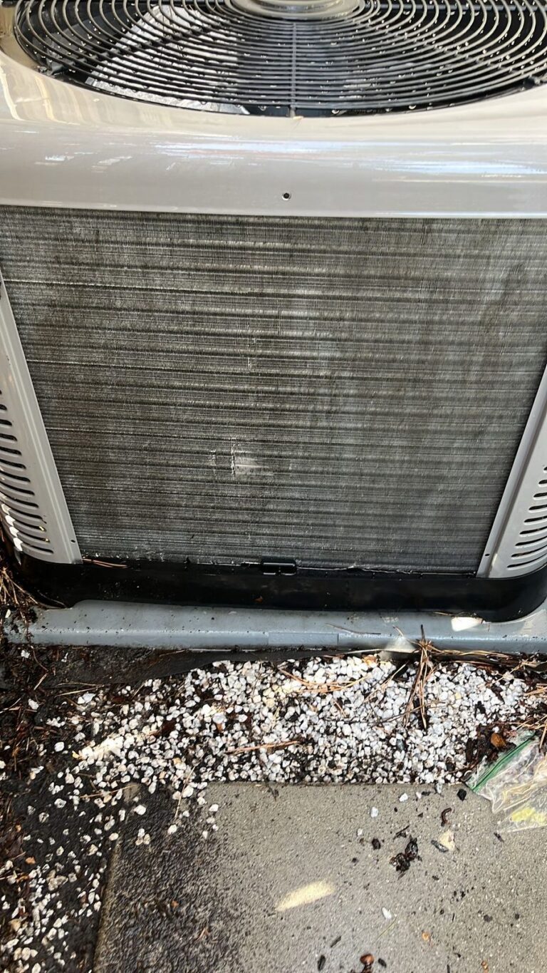 Outdoor AC condenser unit with debris packed against the coil