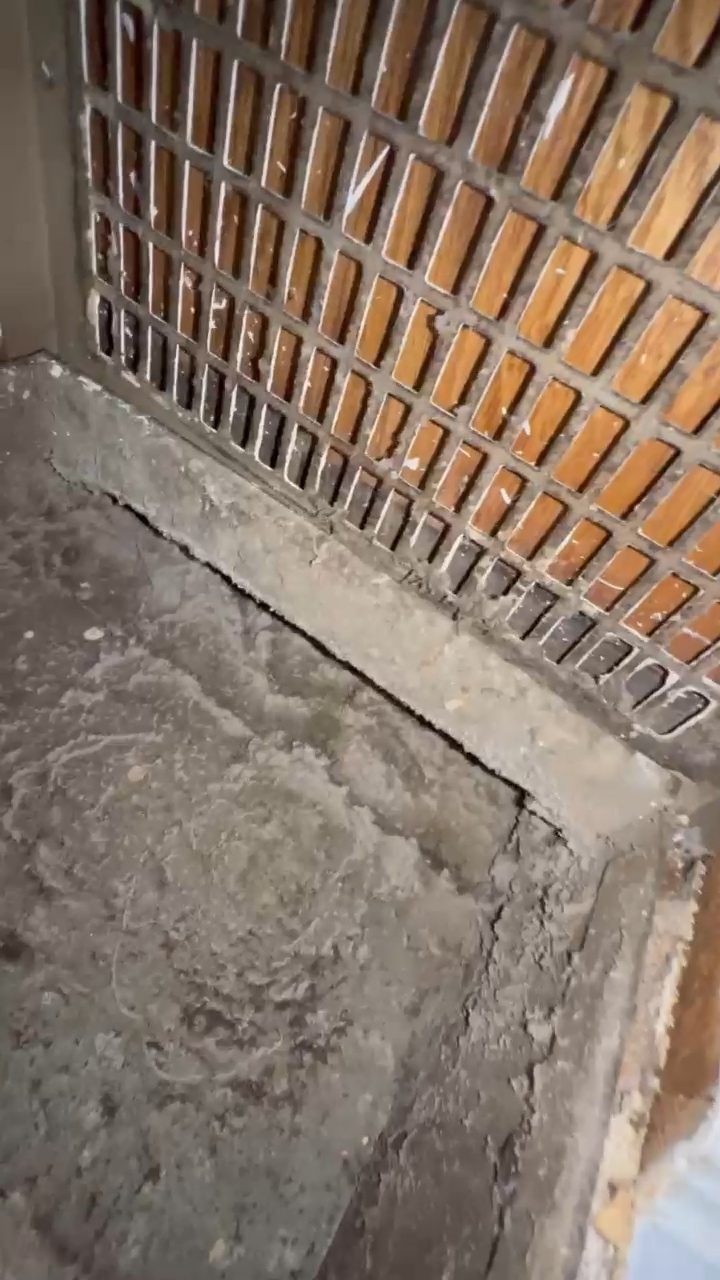 Dust and lint packed under a wooden floor register before duct cleaning