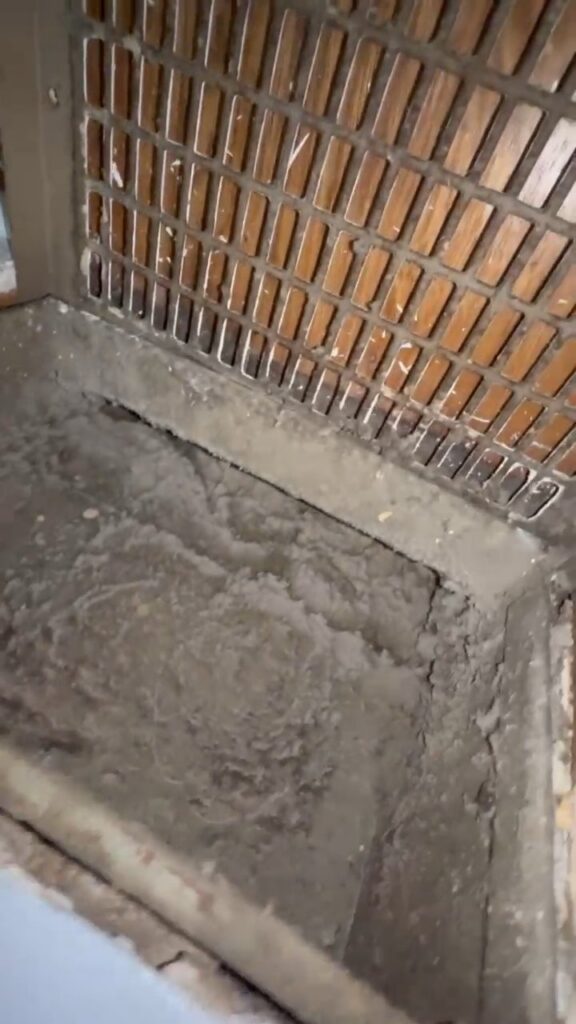 Heavy dust buildup in a return air vent beneath a floor register