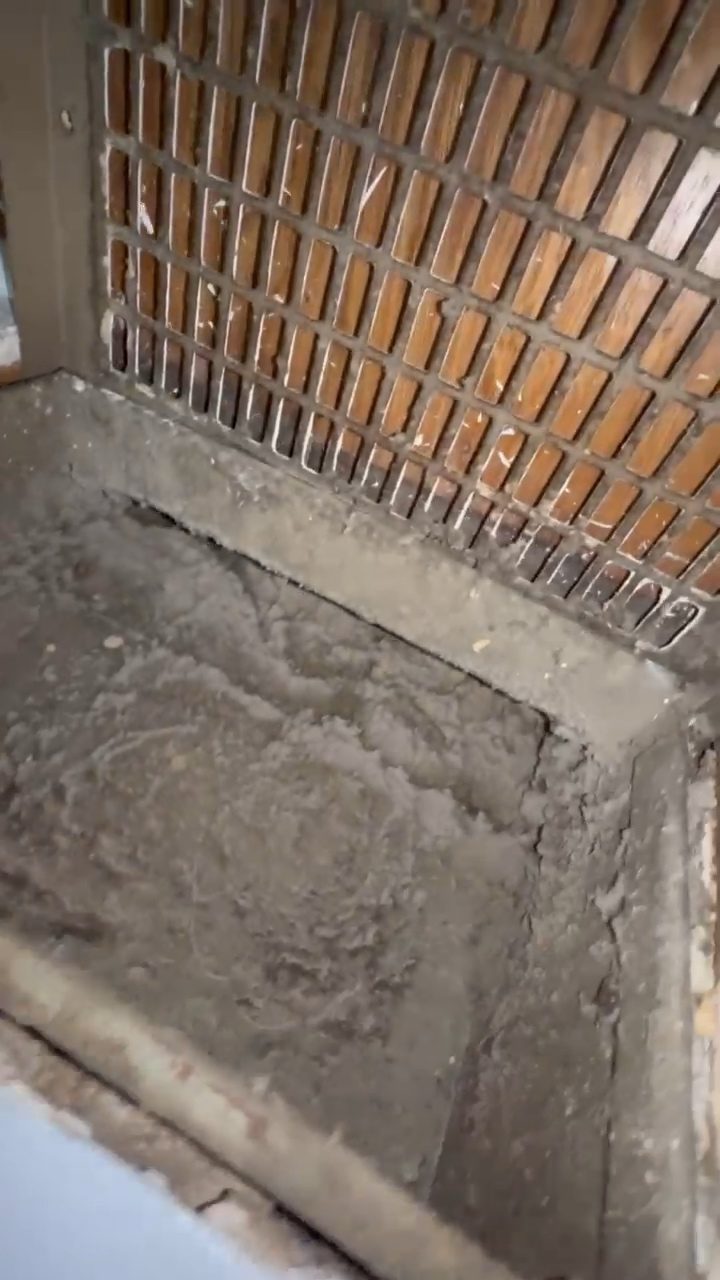 Heavy dust buildup in a return air vent beneath a floor register